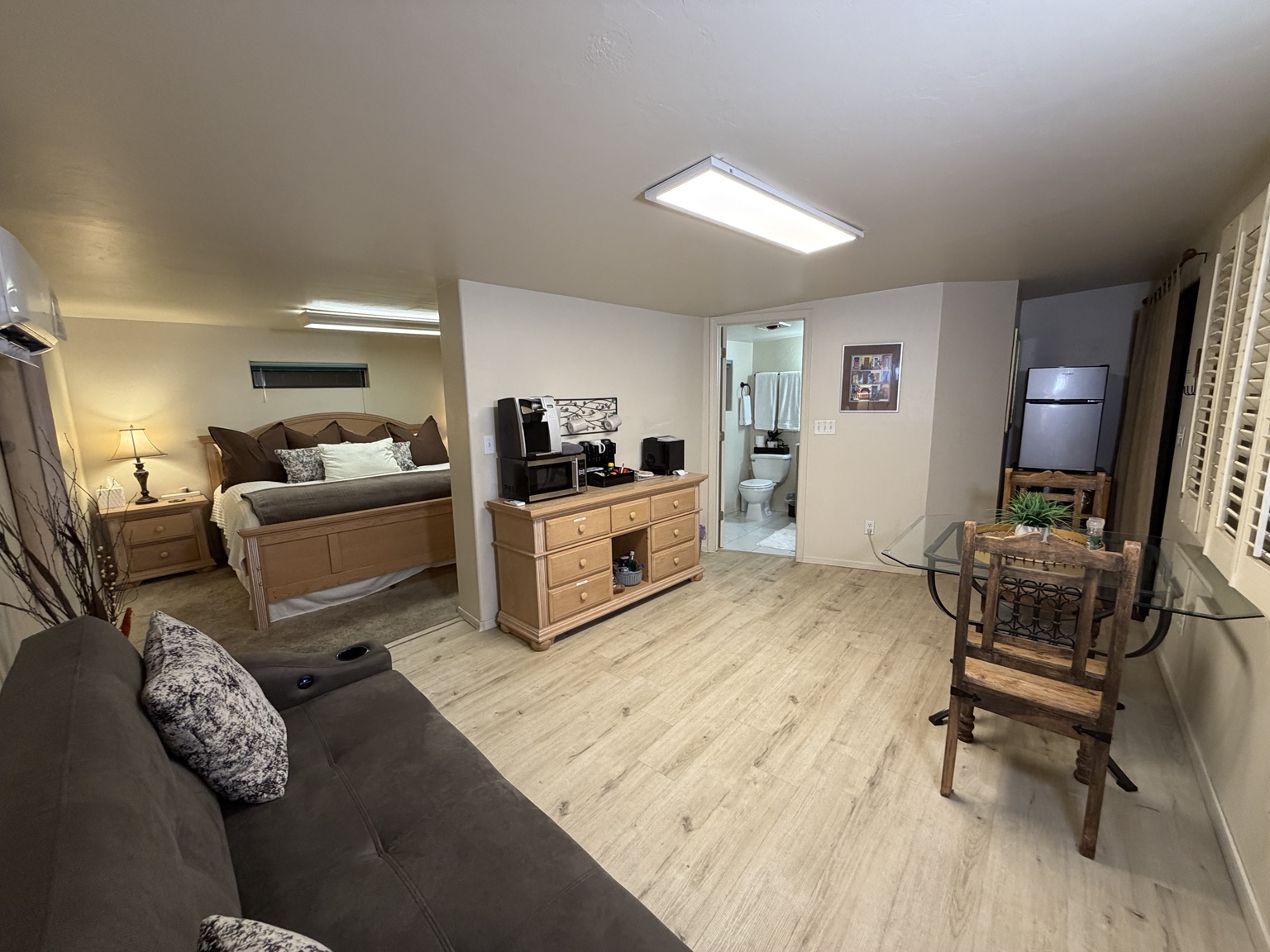 Wide view of the casita showing the king bed, couch, dining table, indoor amenities, and bathroom entrance