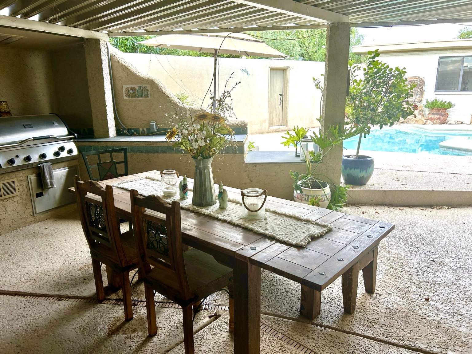 Covered outdoor kitchen and dining table beside the pool