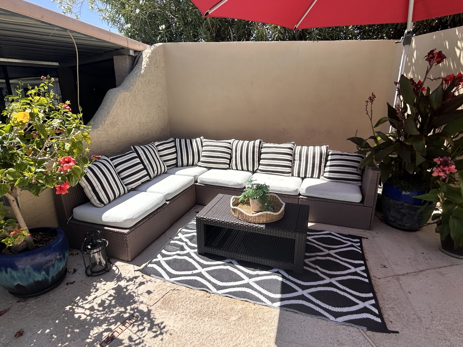 Cushioned sectional seating surrounded by potted flowers on the patio