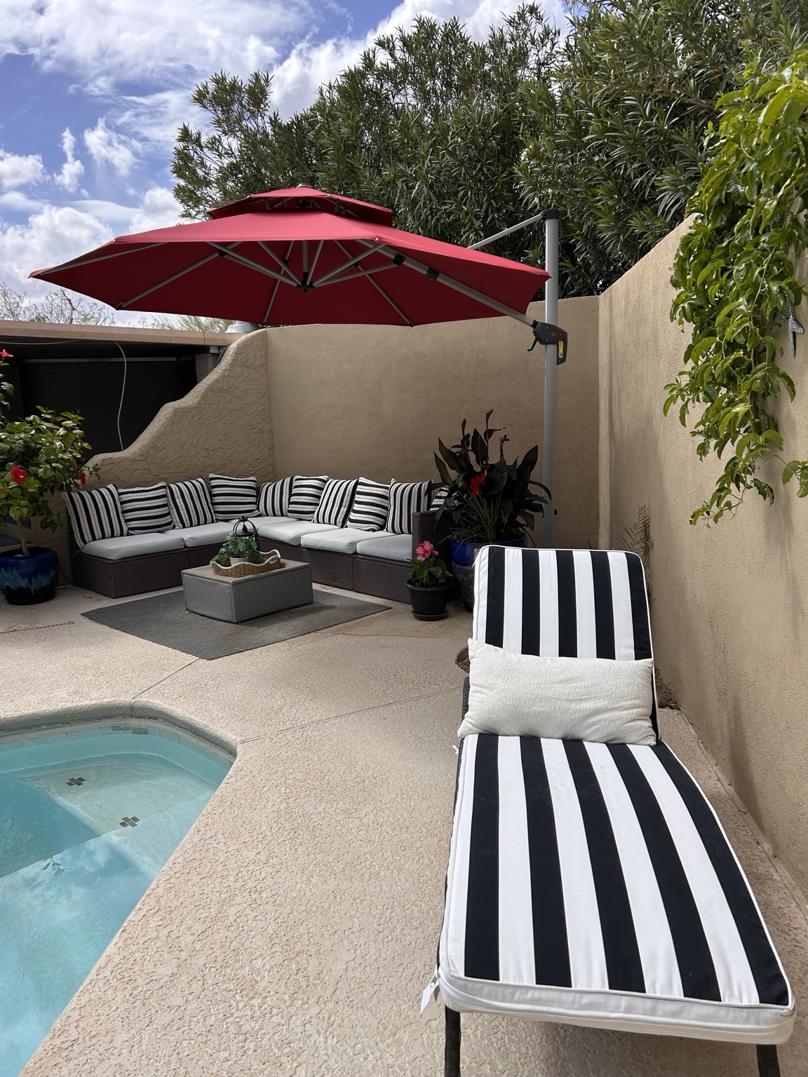 Poolside lounge chair, red umbrella, and cushioned patio seating